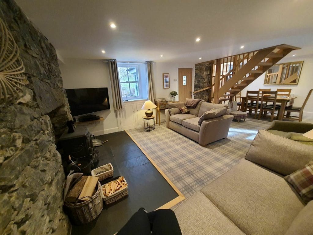 Hawthorn Brae living room with 2 sofas, fireplace, TV, and dining area in the background.