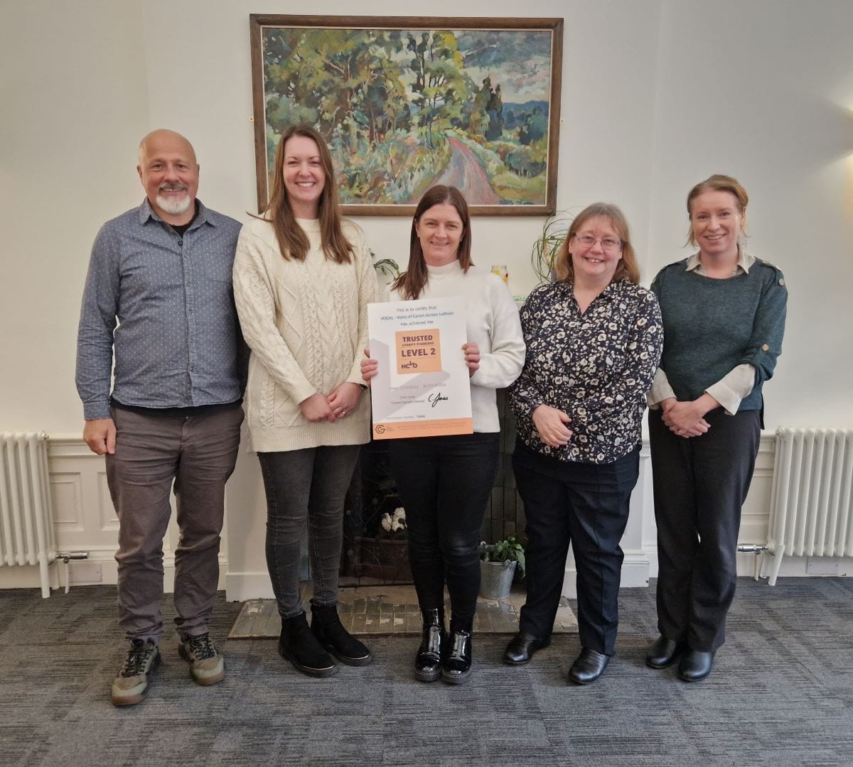 5 VOCAL employees, Andy, Laura, Pauline, Lesley and Rosie stand proudly with our certificate for Trusted Charity accreditation.