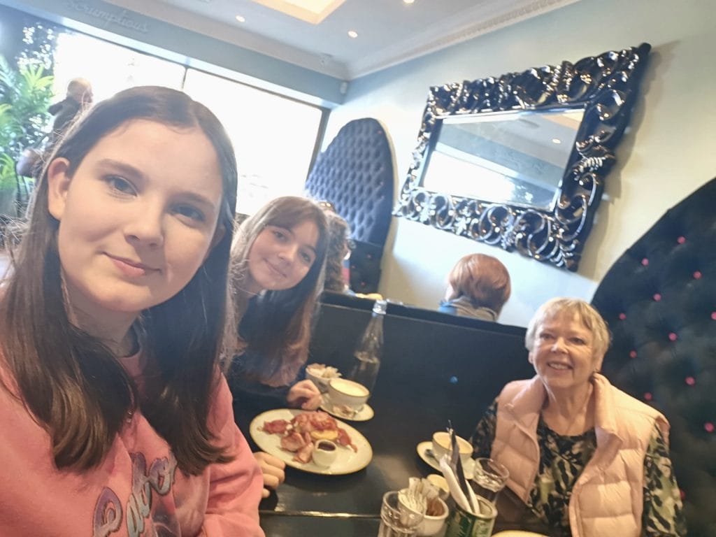 Nicky and two of her grandchildren eating together at a cafe, smiling for a selfie.