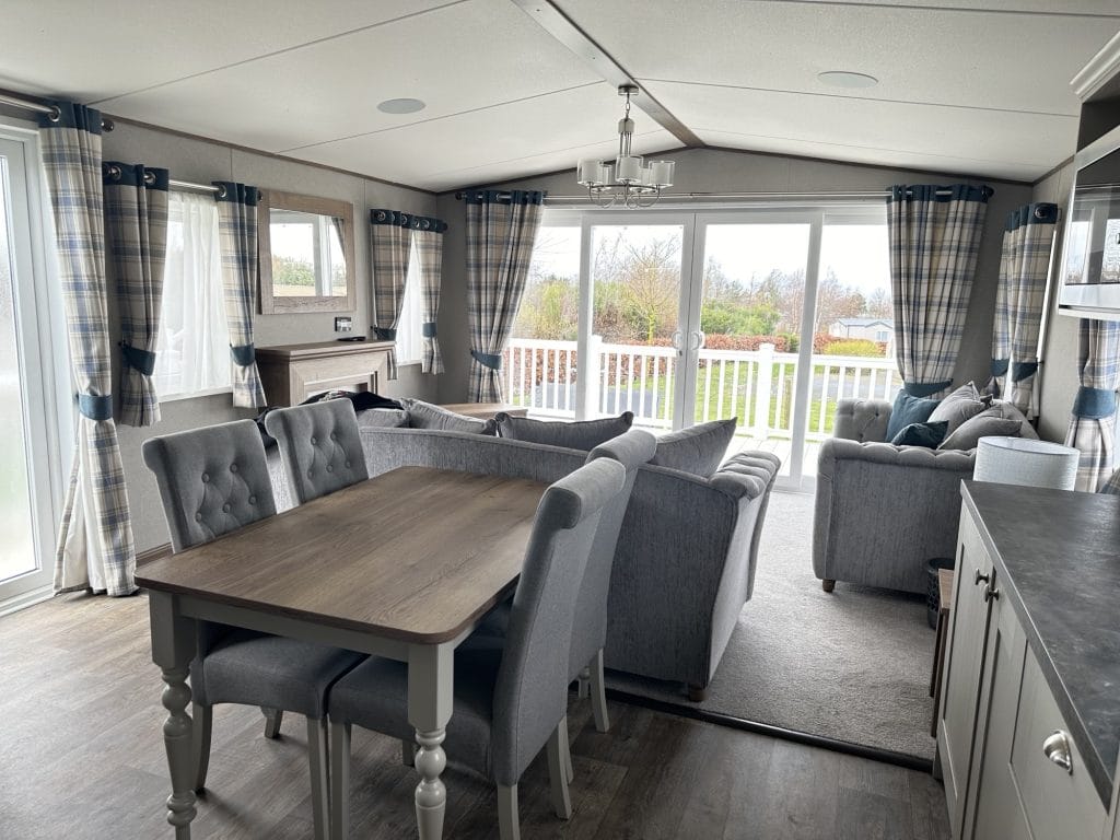 Dining area in Seton Sands holiday home, next to sofa area looking out through the front windows.