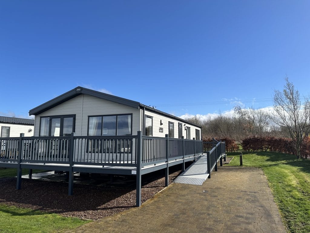 Front view of a Seton Sands holiday home and garden, with a ramp leading up to the wrap-around porch.