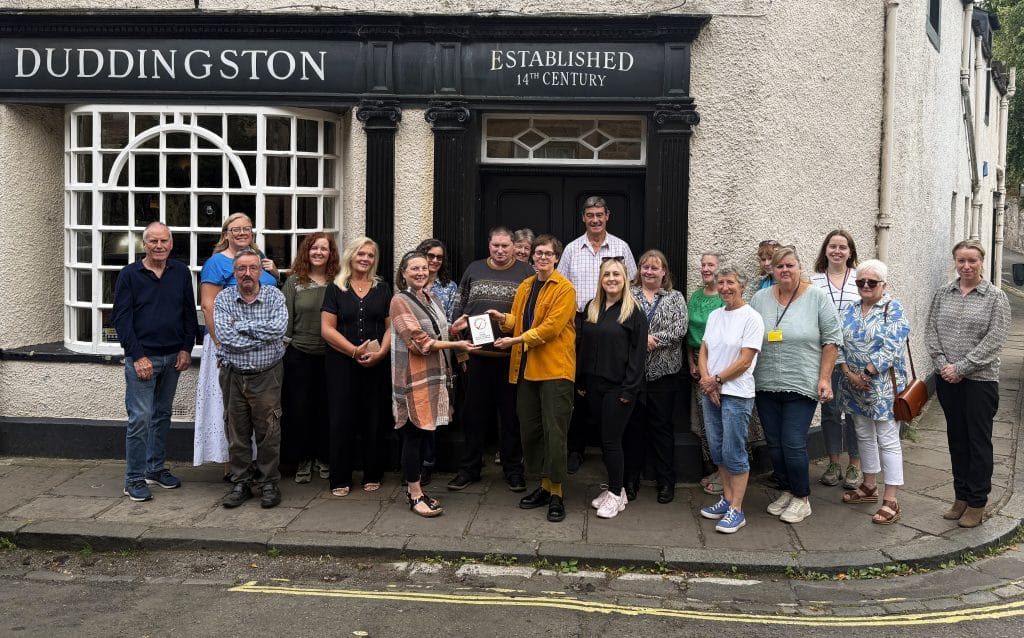 VOCAL staff and volunteers hold the Investing in Volunteers plaque.