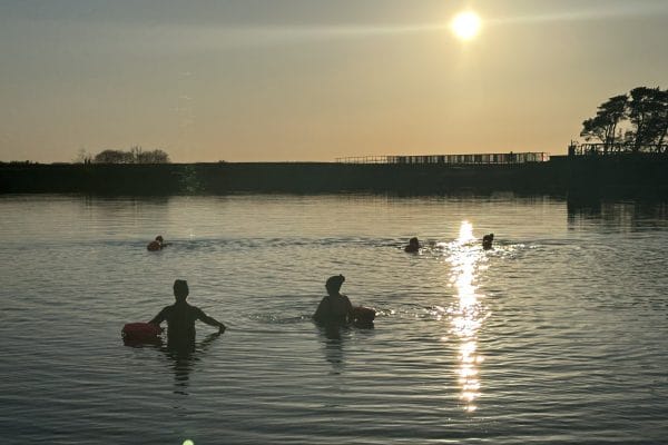Group of women swimming at sunset.